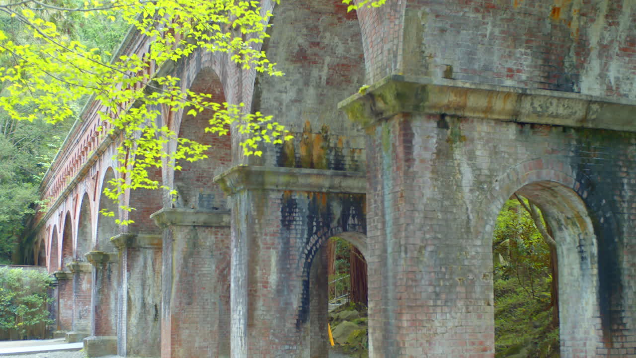 일본 교토의 부드러운 조명을 배경으로 아름다운 나무로 둘러싸인 벽돌 다리