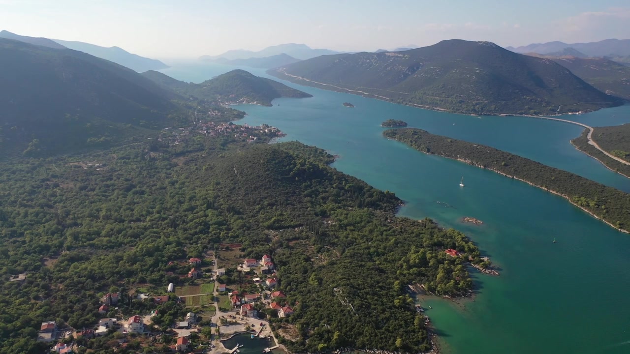Panorama deslumbrante de drone sobre a costa acidentada da Croácia. A cena apresenta ilhas verdes exuberantes, canais marítimos profundos e pequenas vilas costeiras aninhadas entre montanhas majestosas e águas turquesas.