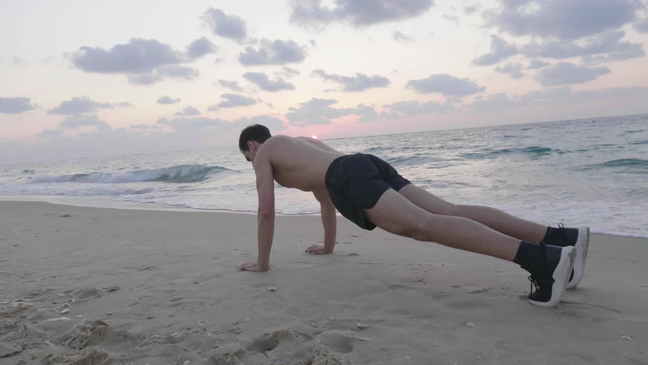 un hombre guapo en forma haciendo ejercicio en la playa al atardecer realizando flexiones