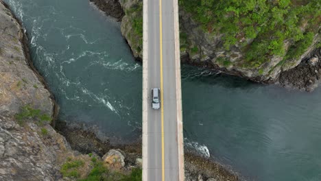 overhead shot of cars driving over a bridge with water passing underneath