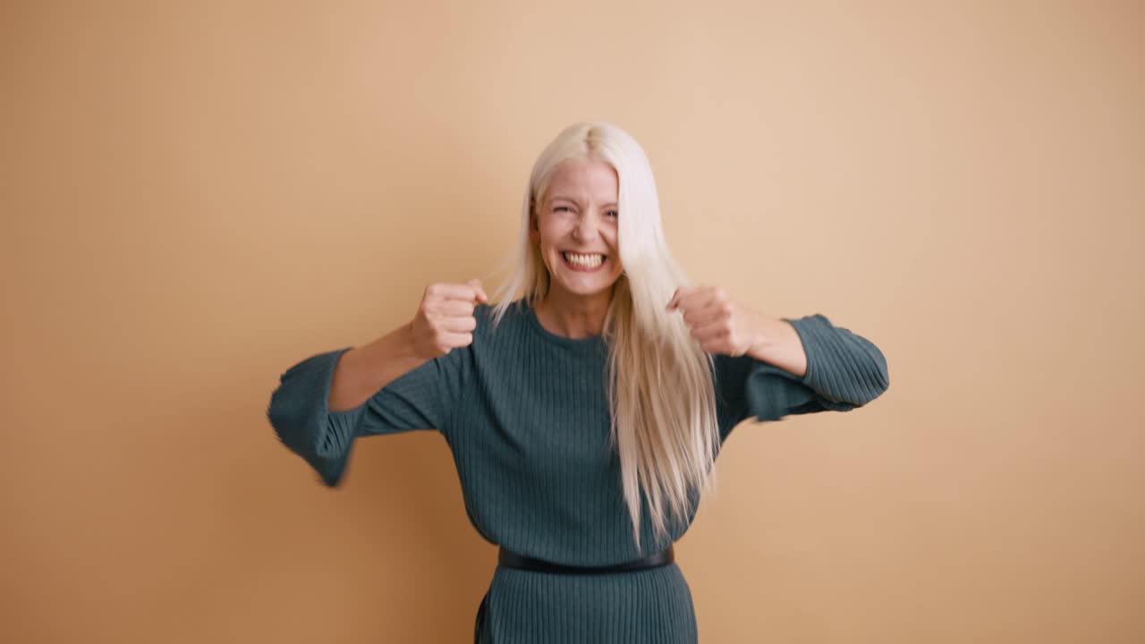 Giovane donna bionda che celebra il successo con espressione gioiosa
