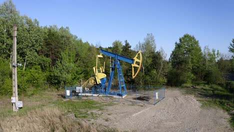 oil pump equipment at work on the landscape surrounded with green forest near campina, romania