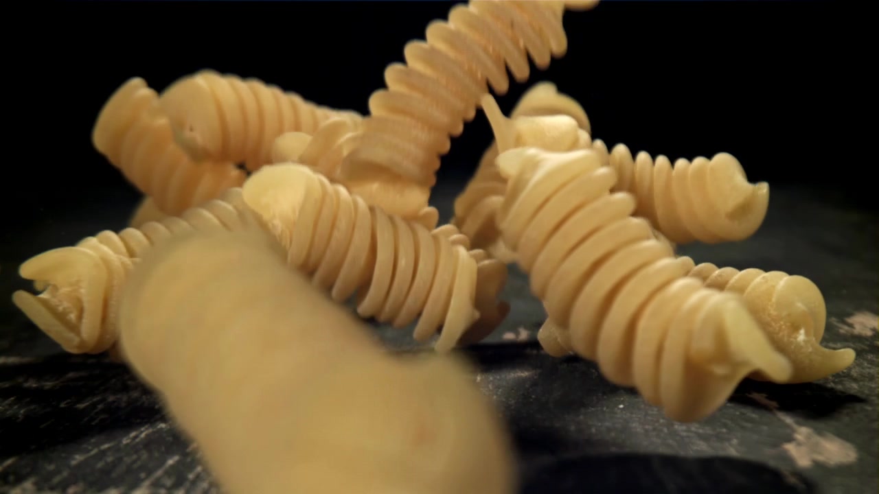 Fusilli in caduta al rallentatore su una superficie scura