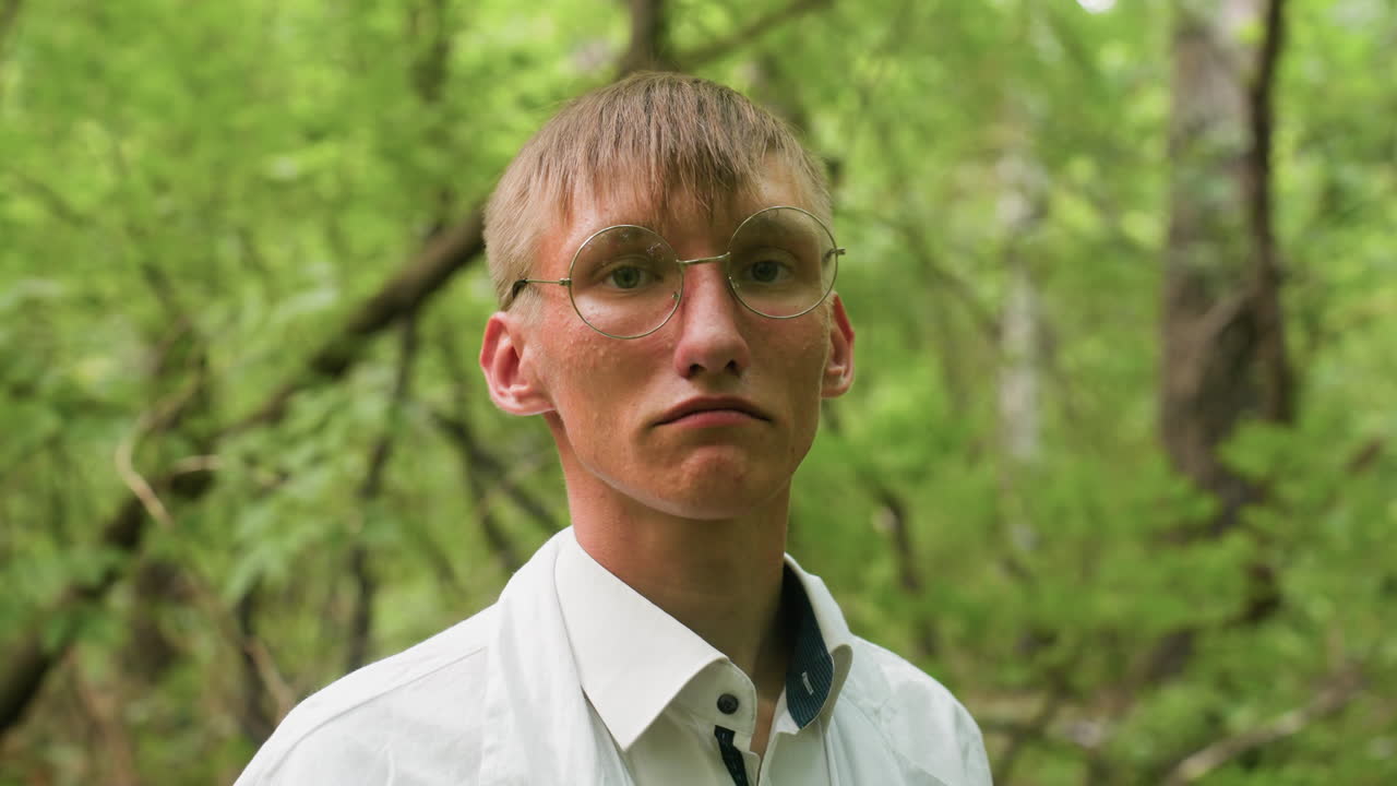 Portrait view of young scientific researcher in white coat standing in forest looking focused, surrounded by lush greenery and soft natural light, emphasizing outdoor preparation, concentration