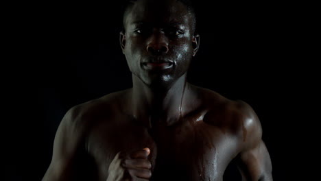 Shirtless-man-jogging-against-black-background