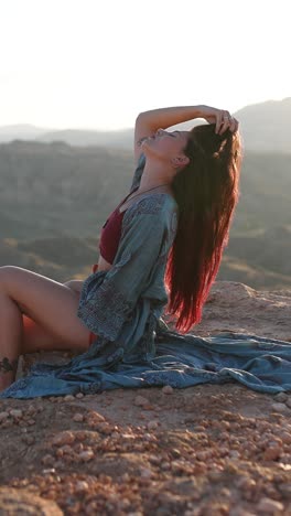 woman posing on a cliff edge at sunset