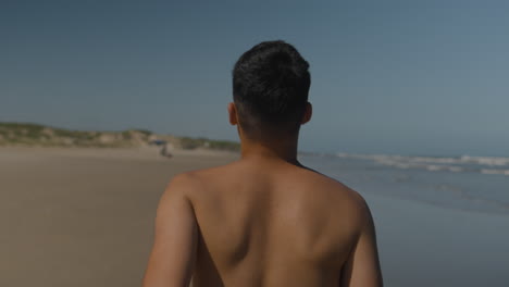 un joven corriendo por la arena.