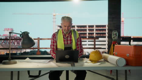 Engineer or Architect Working on Laptop at a Construction Site