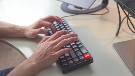 hands form a young man skillfully types out another program in this expertly lit computer scene