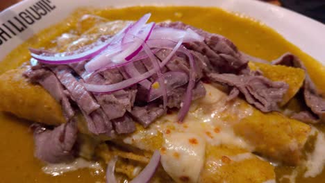 gourmet mexican food: traditional dish topped with red onion and beef