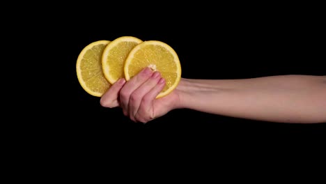 a woman's hand holds three slices of a ripe bright orange in her hand. 4k video.