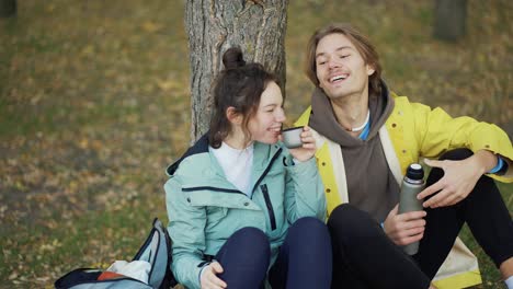 Los-Jóvenes-Viajeros-Se-Sientan-En-La-Naturaleza-Descansando-Bebiendo-Té-Del-Termo-Disfrutan-De-Una-Bebida-Caliente-Descansando.