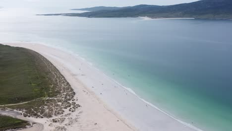 High-elevation-drone-shot-of-Luskentyre-Beach,-tilting-to-show-members-of-the-public
