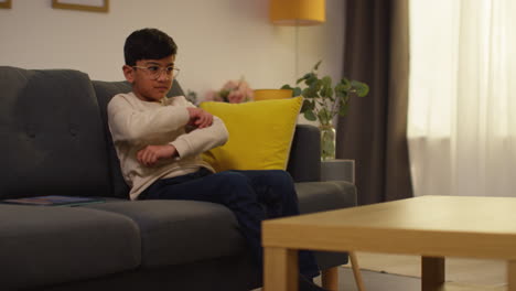 young boy sitting on sofa at home fed up with playing games or streaming onto digital tablet 2