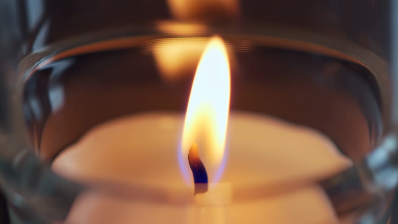 Closeup Candle Flame Glowing Inside Glass, Warm Amber Light Reflecting On Curved Votive, Steady Flicker