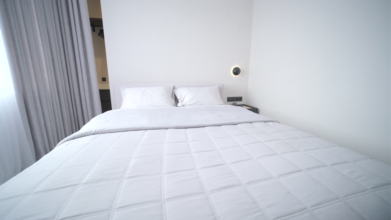 Interno camera da letto moderno e pulito con letto bianco e arredamento minimalista.