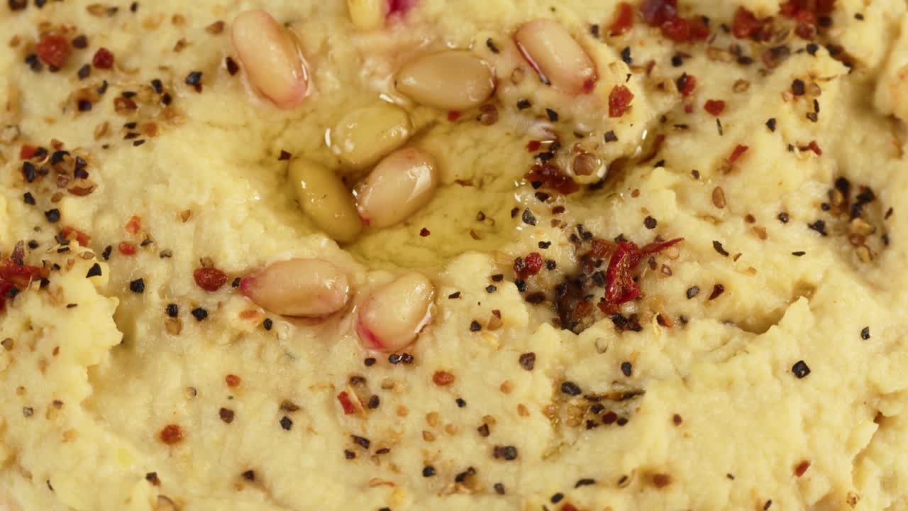 cocina israelí. textura de hummus decorada con especias de primer plano. comida nacional, cultura de oriente medio. bocadillo de puré de garbanzos vegano. aperitivo hecho de puré