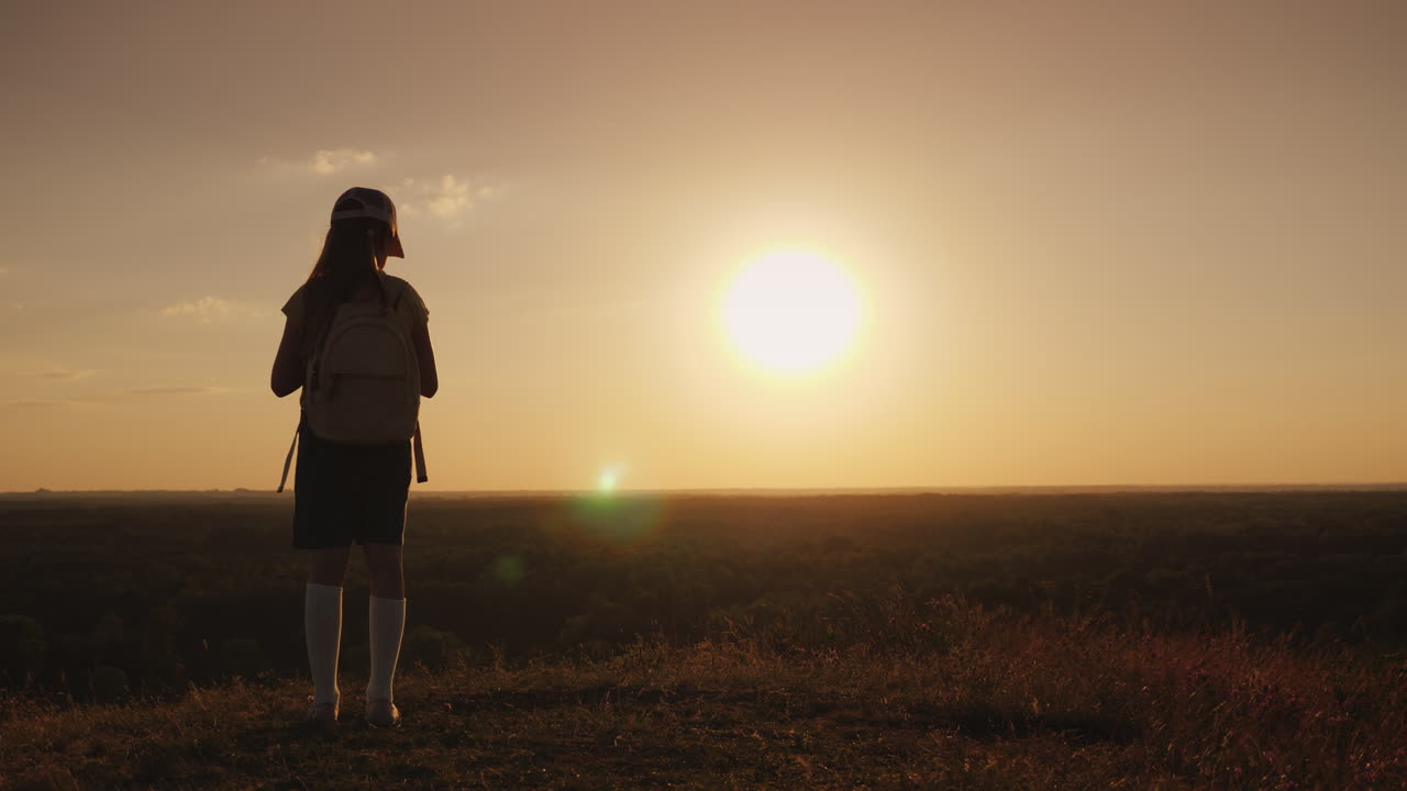 una ragazza con uno zaino è in un luogo pittoresco in attesa del tramonto un piccolo viaggiatore e