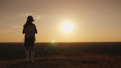 A-Girl-With-A-Backpack-Is-In-A-Picturesque-Place-Looking-Forward-To-The-Sunset-A-Little-Traveler-And