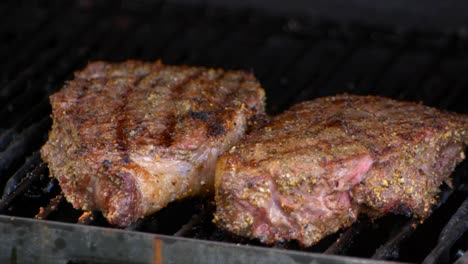 two thick and juicy rib eye steaks are revealed as a grills lid is lifted up in slow motion