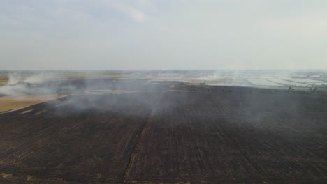 a reverse aerial footage revealing a vast portion of a farm land already tilled charred after burning, grassland burning, pak pli, nakhon nayok, thailand