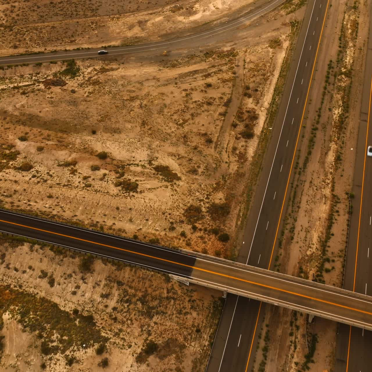 Speedways and freeways built in the desert of California. Cars driving by the roads. Aerial view