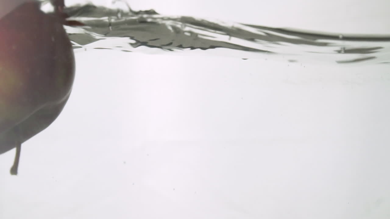 maçã vermelha cai na água em câmera lenta 100 fps