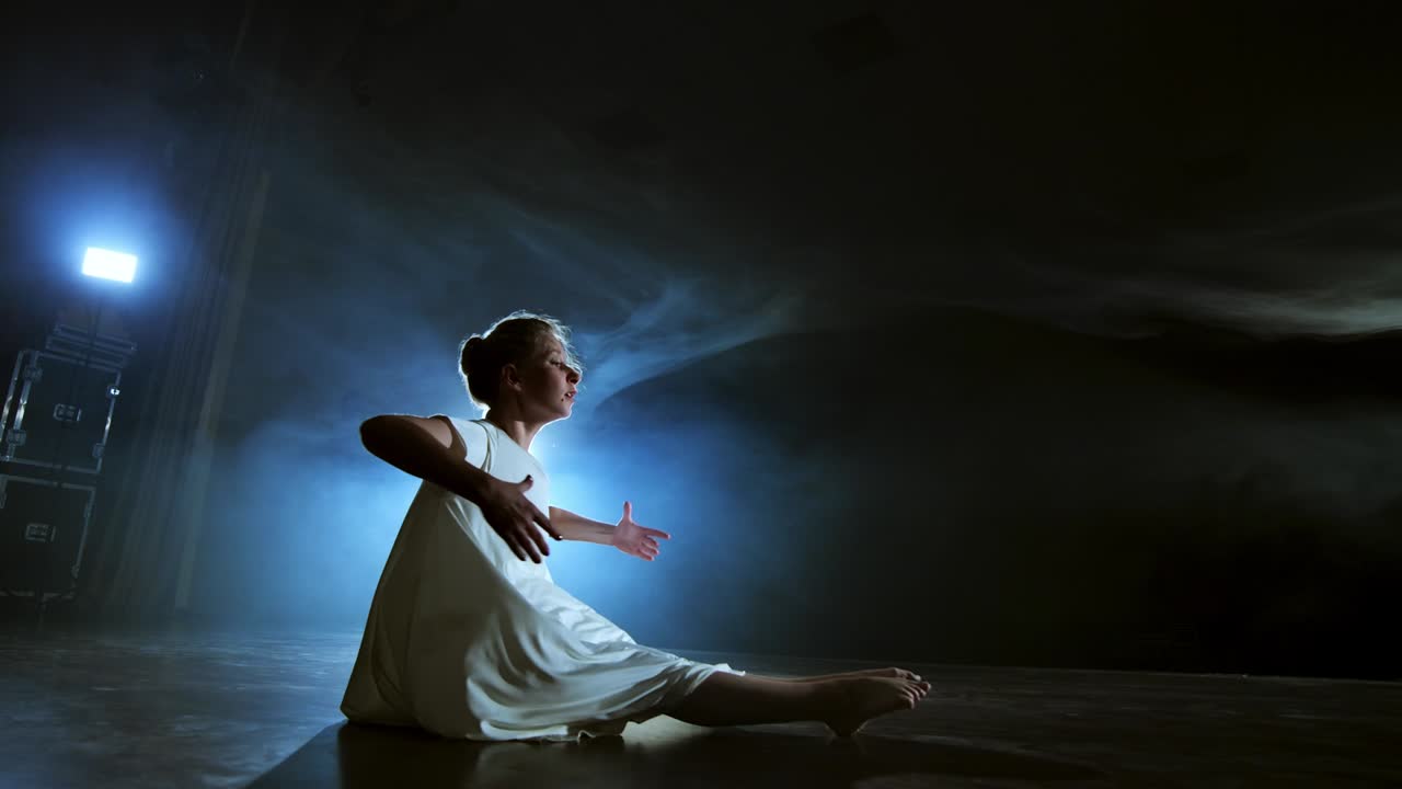 Kvinde i hvid kjole på scene med røg danser moderne ballet
