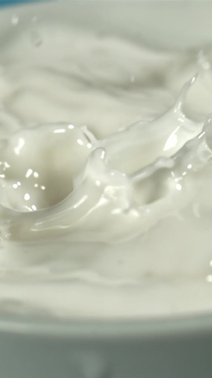 Rallentatore: Gocce di latte che schizzano in un liquido bianco.