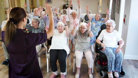 carer leading group of seniors in fitness class in retirement home