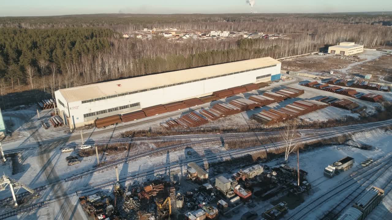 воздушный вид круглых металлических труб на металлическом складе с железнодорожным доступом.