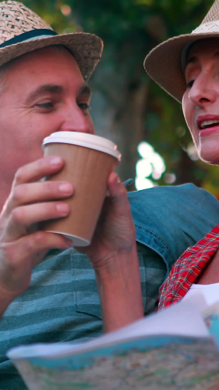 행복 한 관광 부부 가 지도 를 들고 벤치 에 앉아 있다