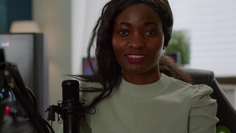 Black-woman-gamer-looking-at-camera-smiling-sitting-in-gaminig-room