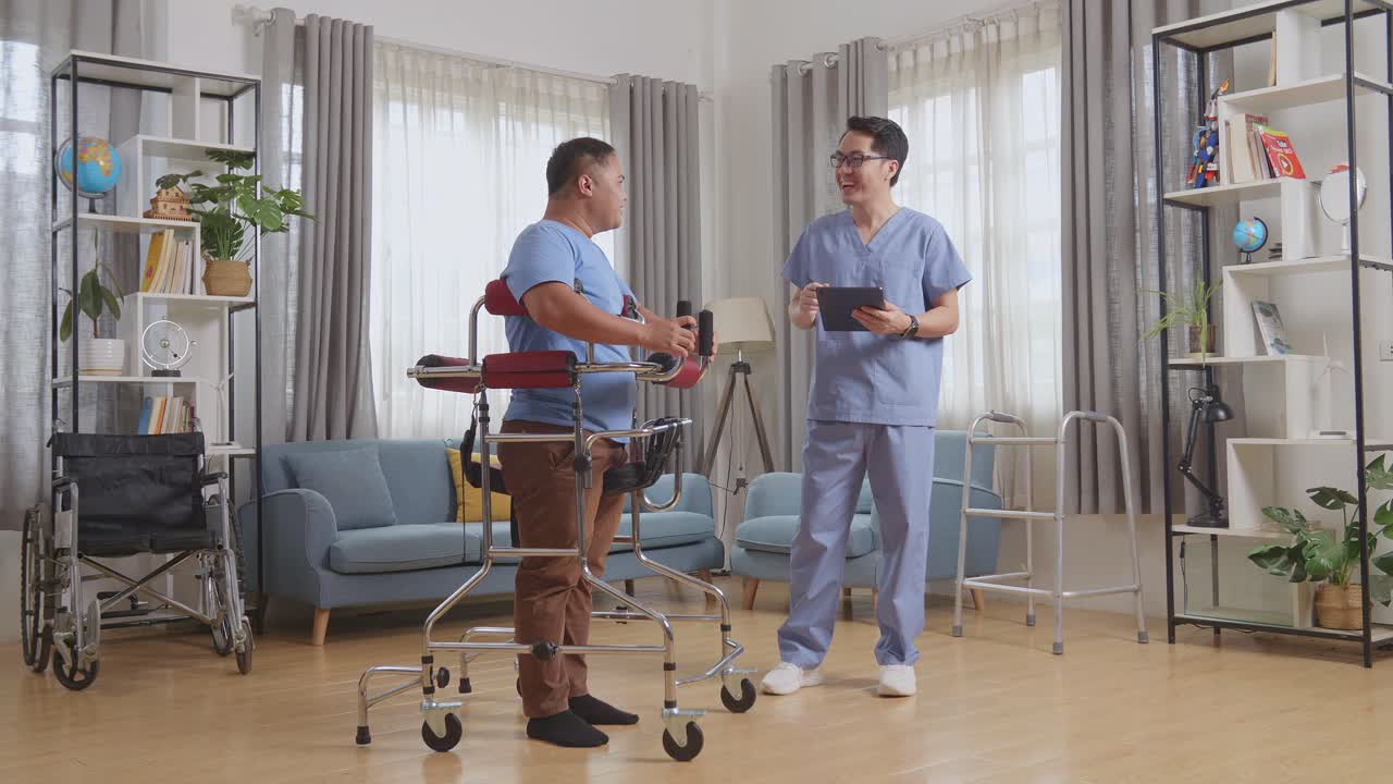 태블릿을 들고 있는 아시아 남성 간호사가 커에 서서 환자와 얘기하고, 웃으며, 집에서 물리 치료를 하는 동안 서로 주먹을 맞대고 있다.