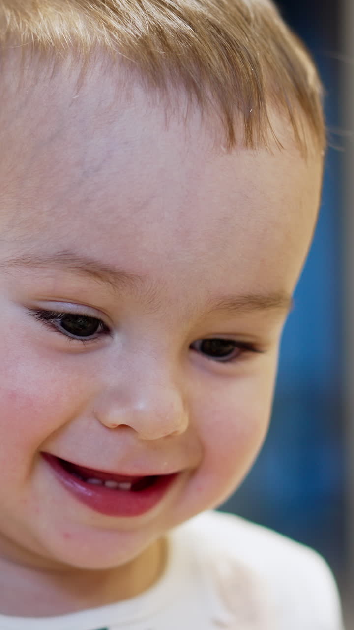 Happy one year old toddler portrait. Smiling Caucasian child close up. Blurred backdrop. Vertical video