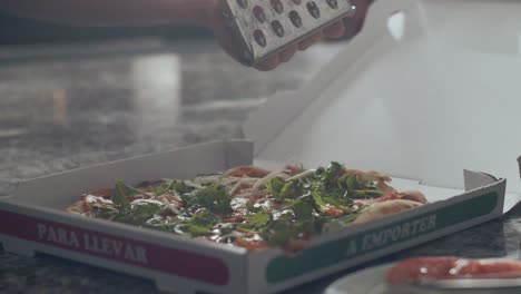 피자이올로 (pizzaiolo) 는 구운 피자 위에 치즈를  ⁇ 는다.