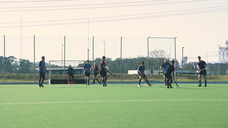 playing field hockey, men competing in outdoor match on green field