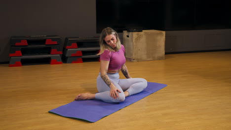 person seated on a gym mat, stretching and engaging in flexibility training to enhance mobility and decrease pressure in neck swaying head