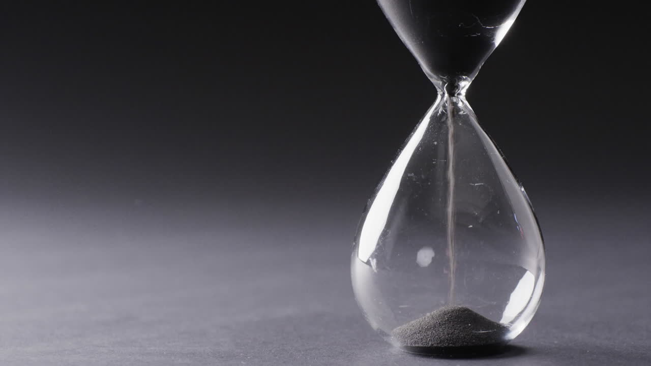 video de reloj de arena con arena vertiendo, copia espacio en fondo negro