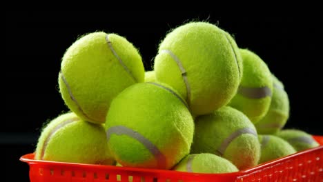 Basket-full-of-tennis-ball-against-black-background