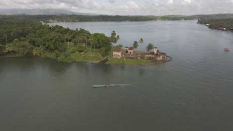 Traditional-wooden-boat-cruising-near-Castello-san-felipe-Guatemala,-aerial