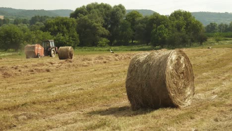 Runde-Goldene-Heuballen-In-Ländlicher-Landwirtschaftsszene-Mit-Traktormaschinen