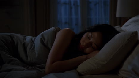a woman sleeping peacefully in a dark bedroom