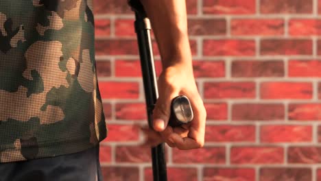 close-up of a person's hand holding a crutch against a brick wall