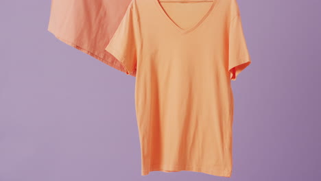 video de un primer plano de camisetas naranjas colgando sobre un fondo púrpura