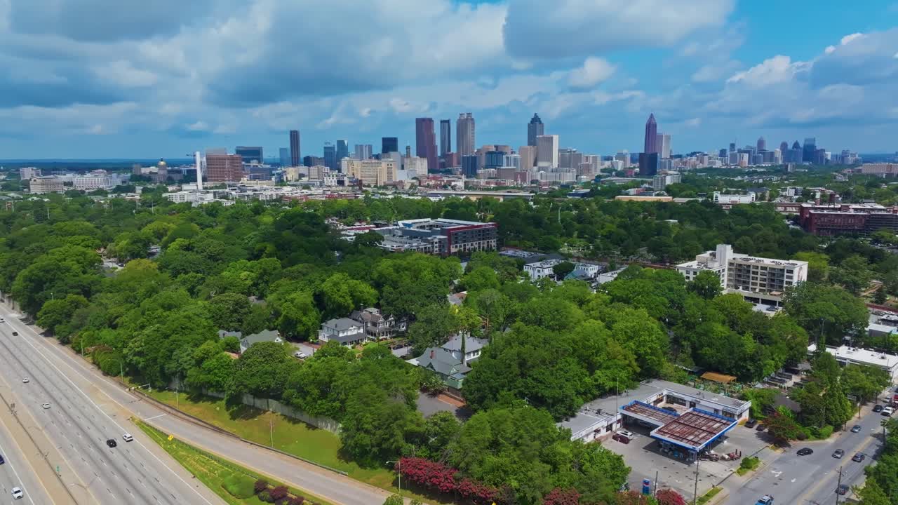 Skyline with skyscrapers of Atlanta city, Georgia on summer day. Traffic scene on highway. Suburb district with green trees and homes. Aerial panorama wide shot. Quiet and peaceful city scene
