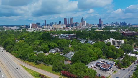 skyline with skyscrapers of atlanta city, georgia on summer day. traffic scene on highway. suburb district with green trees and homes. aerial panorama wide shot. quiet and peaceful city scene