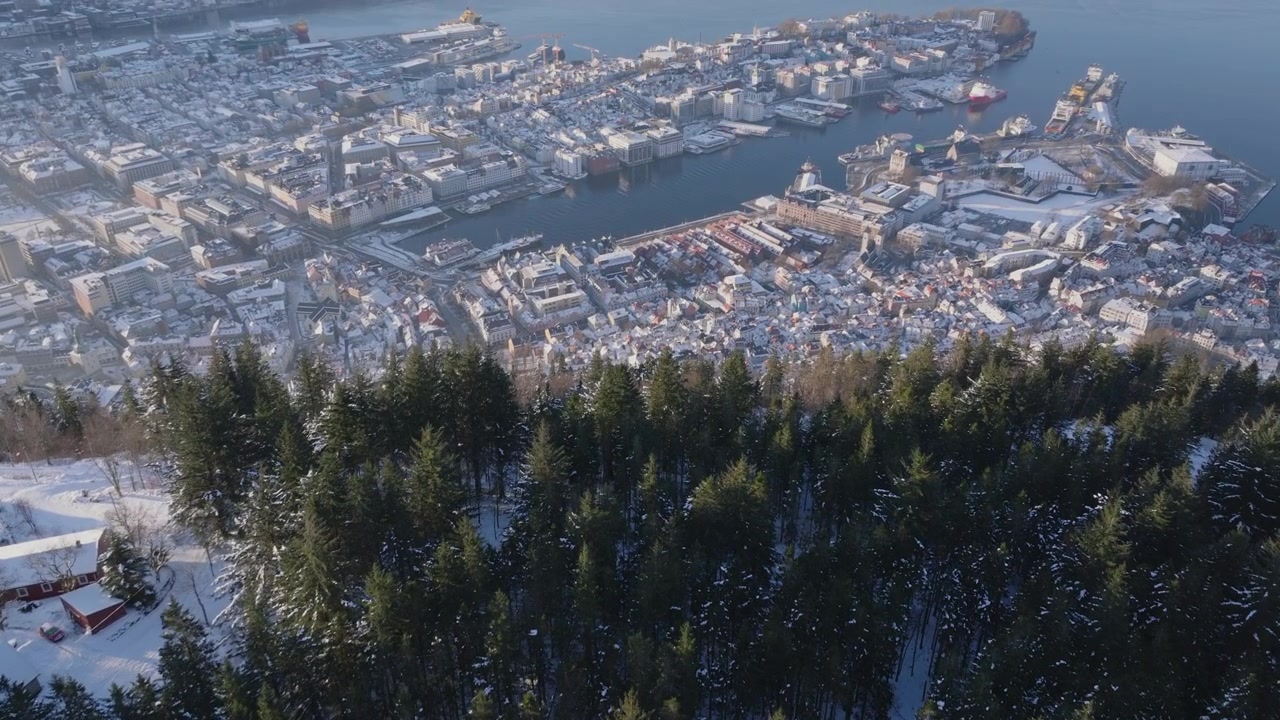 Kinematisk luftfoto som avslører Bergen under de snødekte skogene på Fløyen