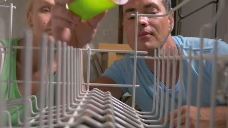 young couple opens the dishwasher and loads there dishes