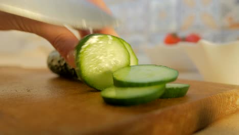 female hands cut a cucumber in the kitchen